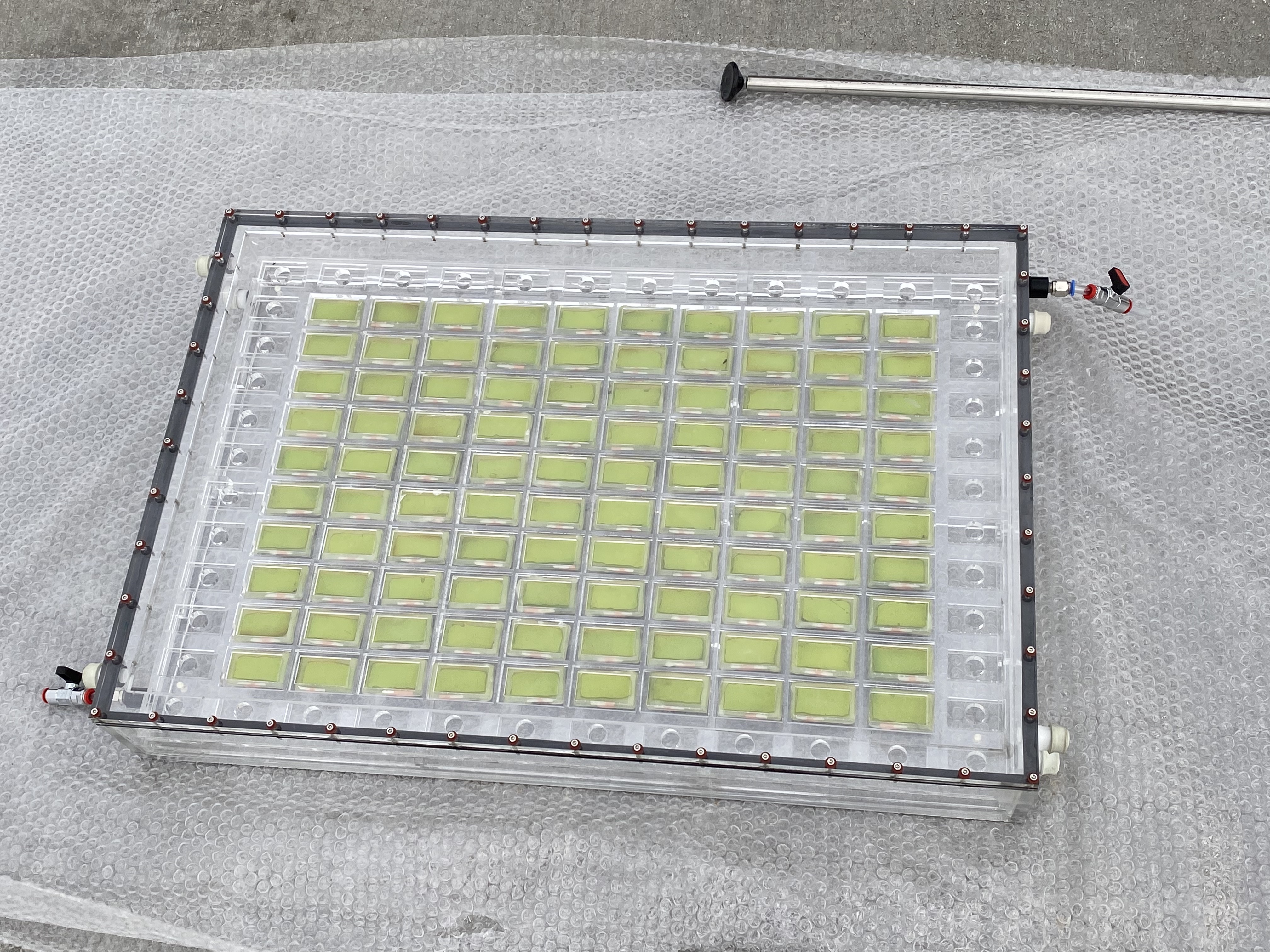 Close up of the demonstrator device: a grid of pale green rectangular cells containing the perovskite panels and catalysts capable of producing syngas from sunlight, carbon dioxide and water