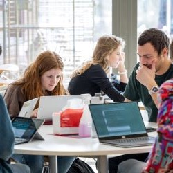 Four people sat round a table with laptops in a cafe setting