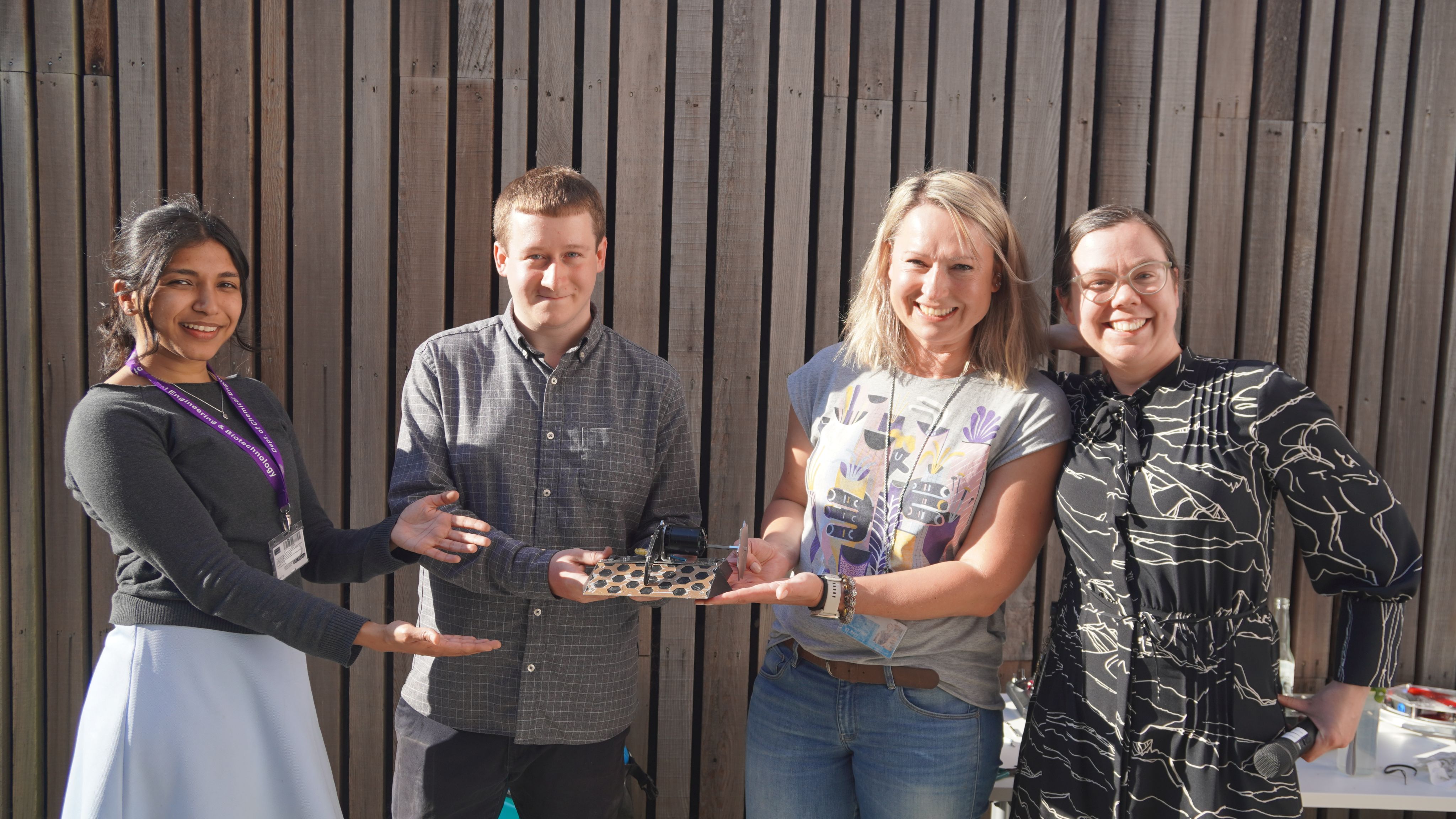 Three women and one man displaying their robot.