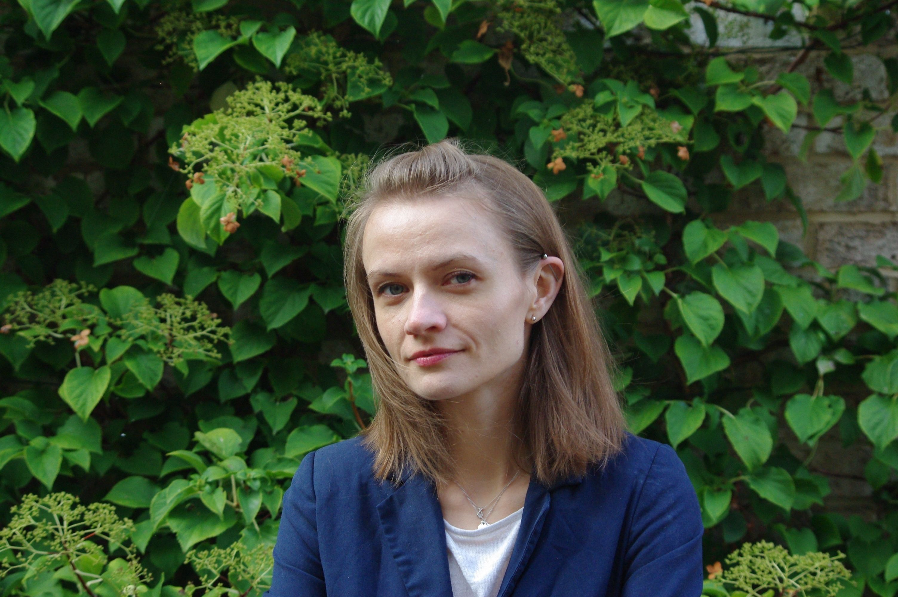 Ewa Marek with hair down looking happily at a camera with a green setting background