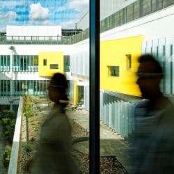 Two people blurred as they walk across corridor with inner courtyard of CEB in background.