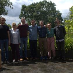Six newly promoted academic staff with head of department Clemens in front of greenery