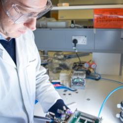 Man in white lab coat working on electronics