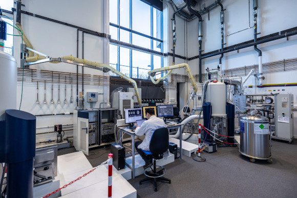 A man sits at a computer in a large laboratory