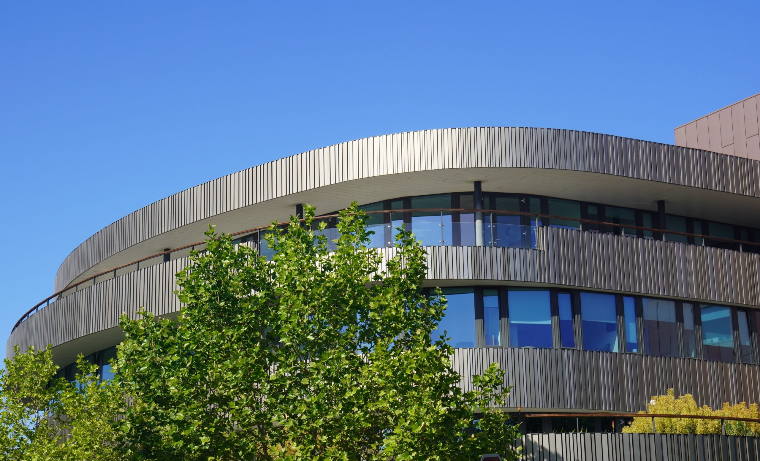 A modern circular university building under a clear blue sky.