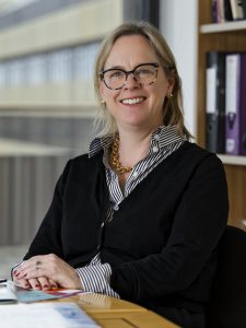 Portrait of a woman with glasses smiling towards the camera