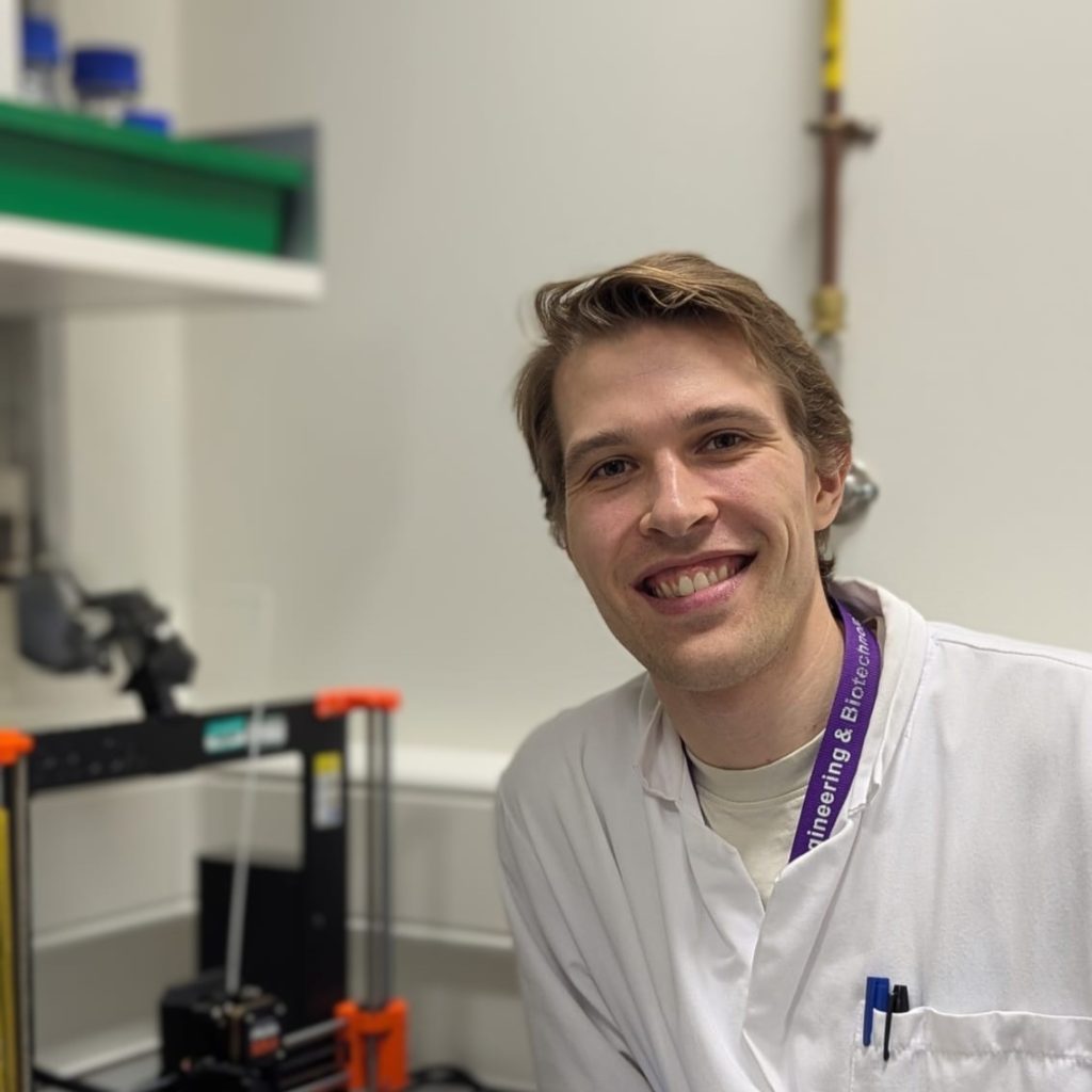 Portrait of a man in a lab coat smiling at the camera.
