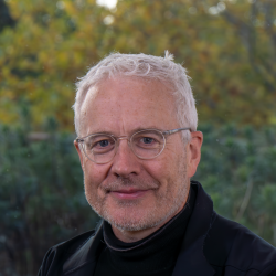 A portrait of a man with glasses smiling towards the camera