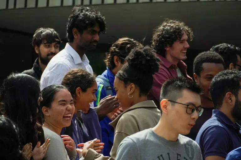 Many smiling young adult faces in sunshine and shadow.
