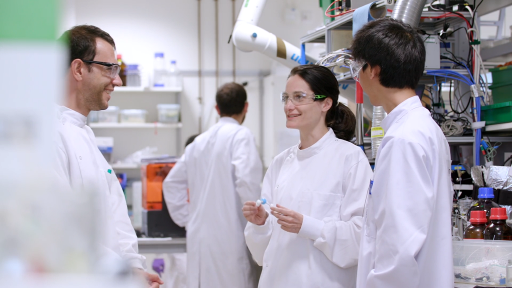A group of scientists have a discussion in a lab setting.
